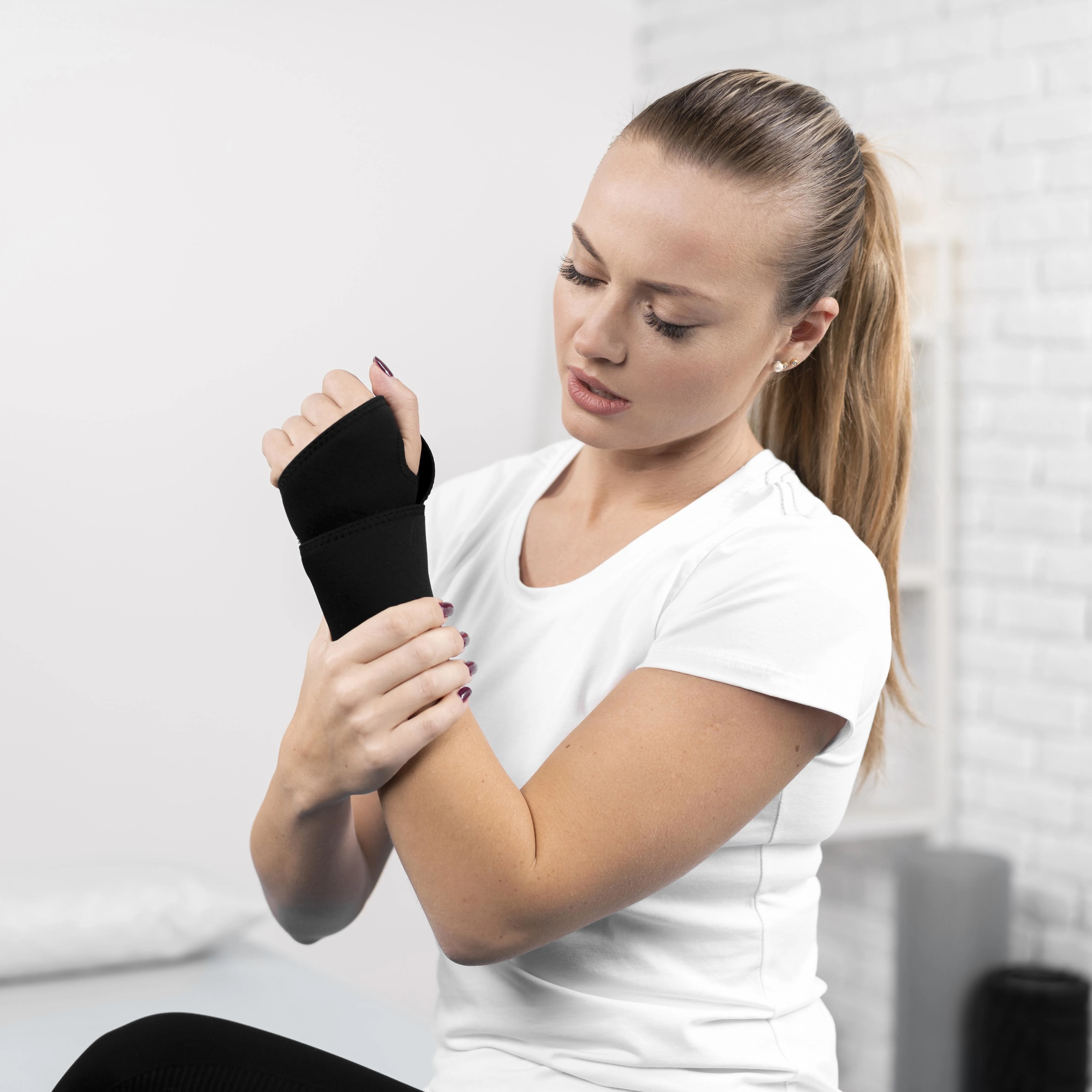 mujer joven con patología y dolores de brazo y muñeca que lleva muñequera y necesita rehabilitación